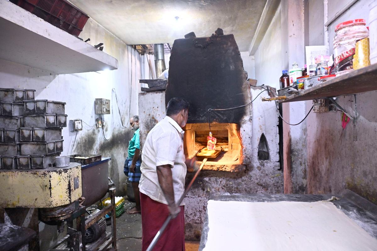 Sakthivel is placing puff dough in the old brick oven in his bakery in Madurai. 