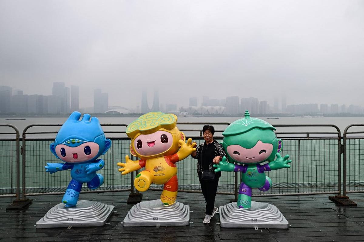 A woman poses for photographs with the 2022 Asian Games mascots (L-R) Chenchen, Congcong and Lianlian along the promenade of Qiantang river in Hangzhou on September 22, 2023. A woman poses for photographs with the 2022 Asian Games mascots (L-R) Chenchen, Congcong and Lianlian along the promenade of Qiantang river in Hangzhou on September 22, 2023.