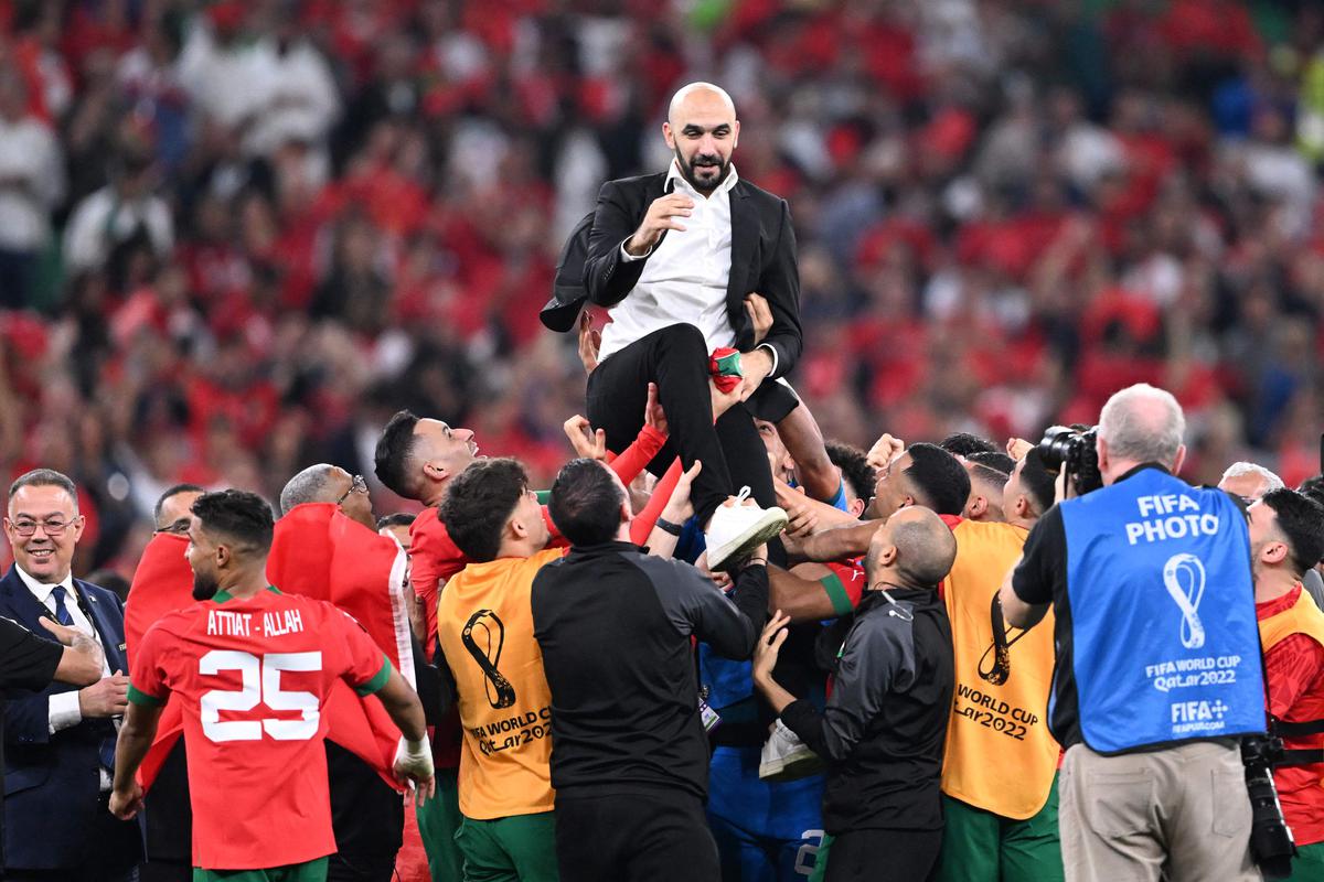 Morocco’s coach Walid Regragui is thrown into the air as players celebrate after winning the quarterfinal match against Portugal.