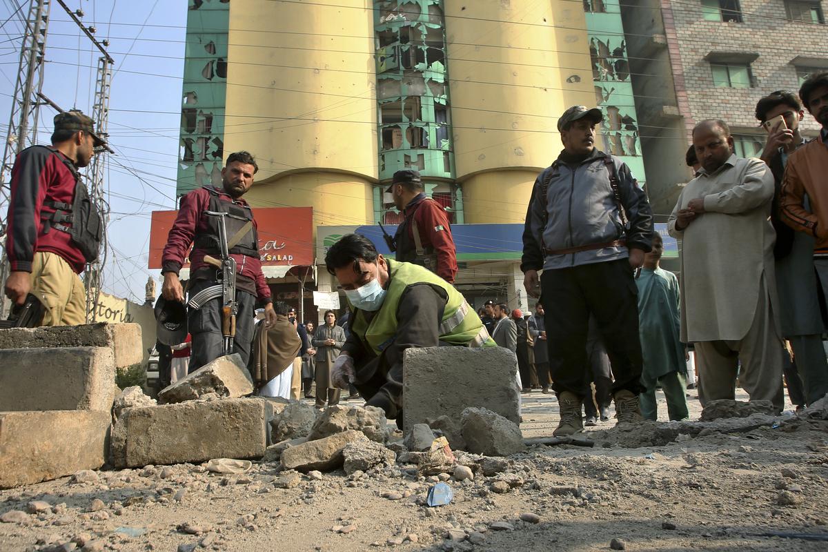 Security officials examine the site of a bomb explosion, in Peshawar, Pakistan, Tuesday, Dec. 5, 2023.