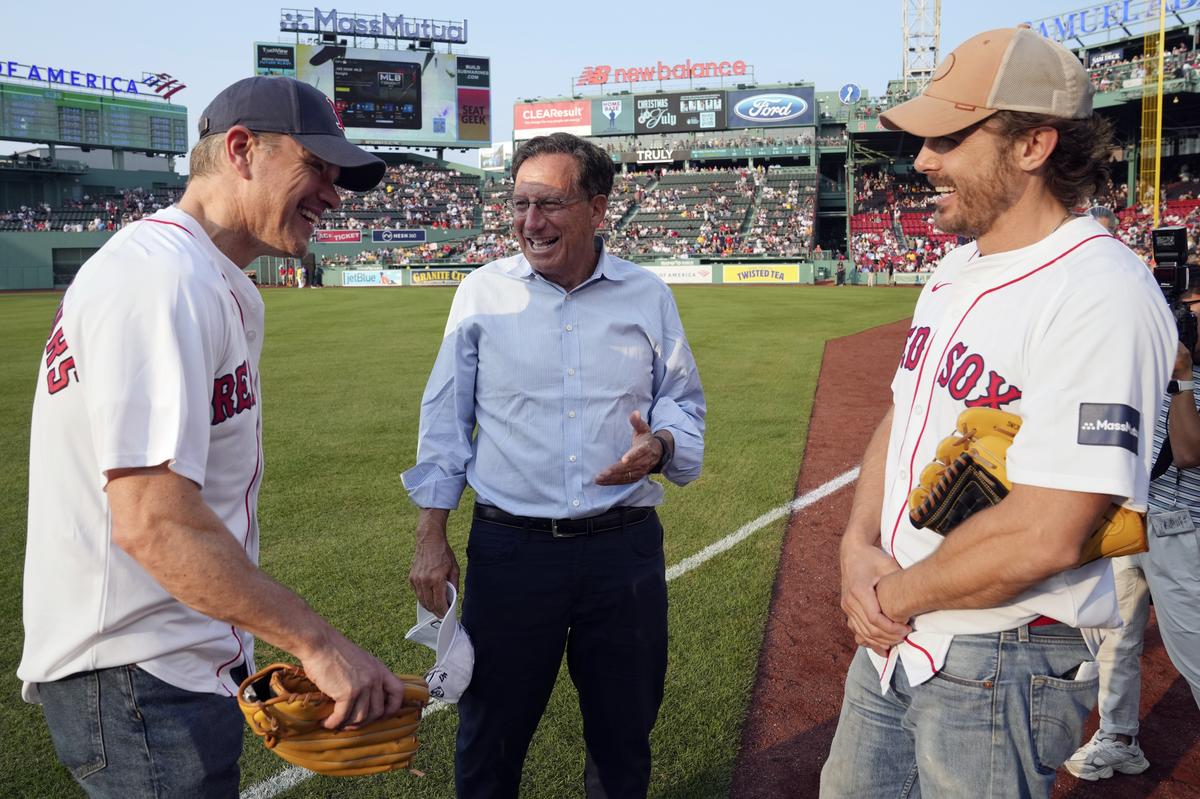 Actors Matt Damon, left, and Casey Affleck, right, talk with Boston Red Sox chairman Tom Werner, center, before a baseball game against New York Yankees in Boston