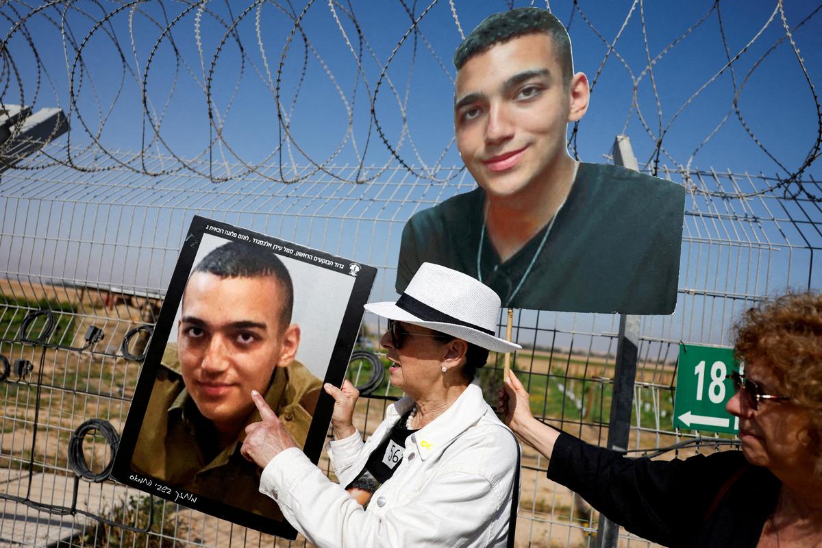 Varda Ben Baruch, grandmother of hostage Edan Alexander, points at the portrait of Edan, as family members and supporters of hostages who were kidnapped during the deadly October 7 attack, stand near the Kibbutz defense to call their captive loved ones over the border between Israel and Gaza, at Kibbutz Nir Oz, in southern Israel on April 20, 2025.