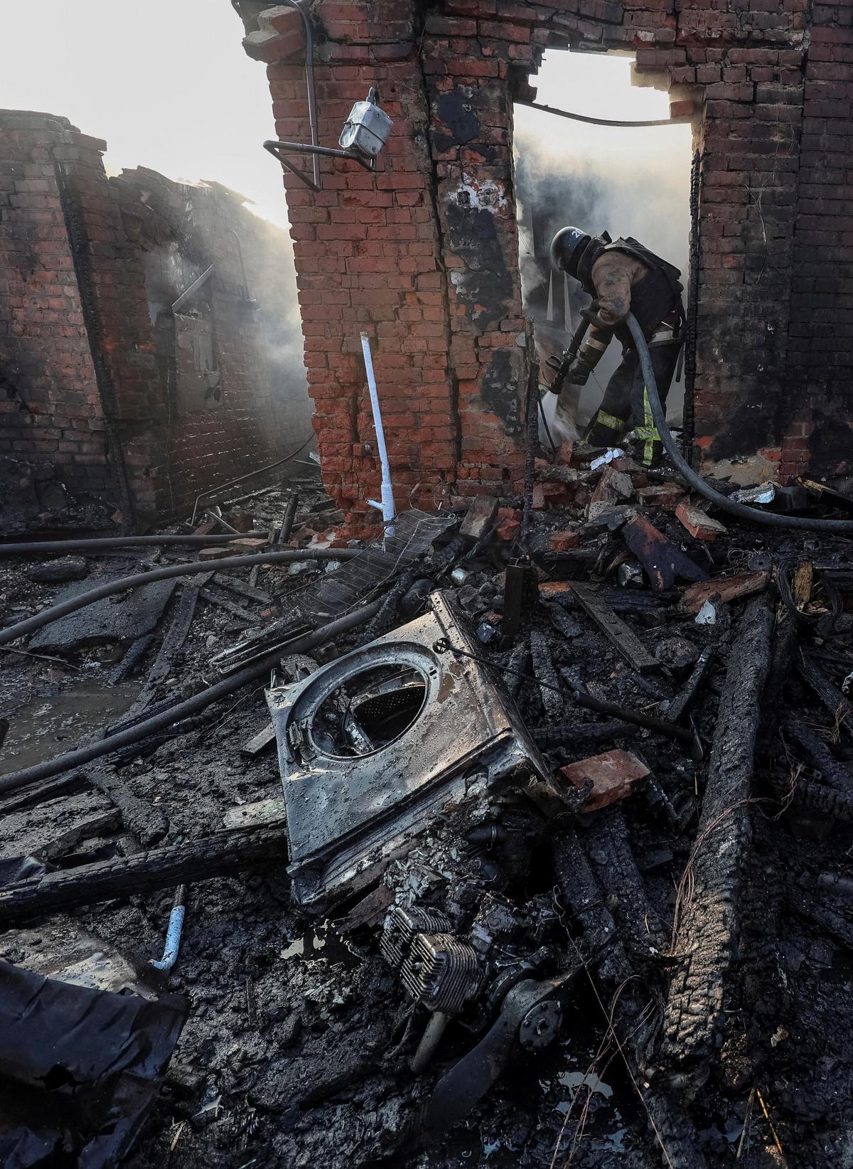 Uma equipe de resgate trabalha no local da casa particular atingida por um ataque de drone russo enquanto o motor de um drone russo está no chão, em meio ao ataque da Rússia à Ucrânia, em Kharkiv, Ucrânia, em 6 de maio de 2026.
