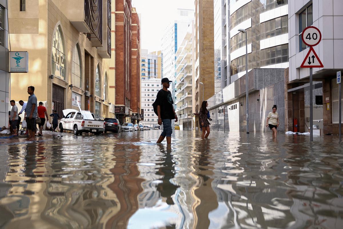 La gente camina entre las inundaciones causadas por las fuertes lluvias, en Dubai, Emiratos Árabes Unidos, el 17 de abril de 2024. 