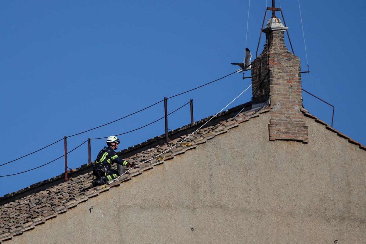 A firefighter works on the roof of the Sistine Chapel to set a chimney, ahead of the conclave, at the Vatican on May 2, 2025. 