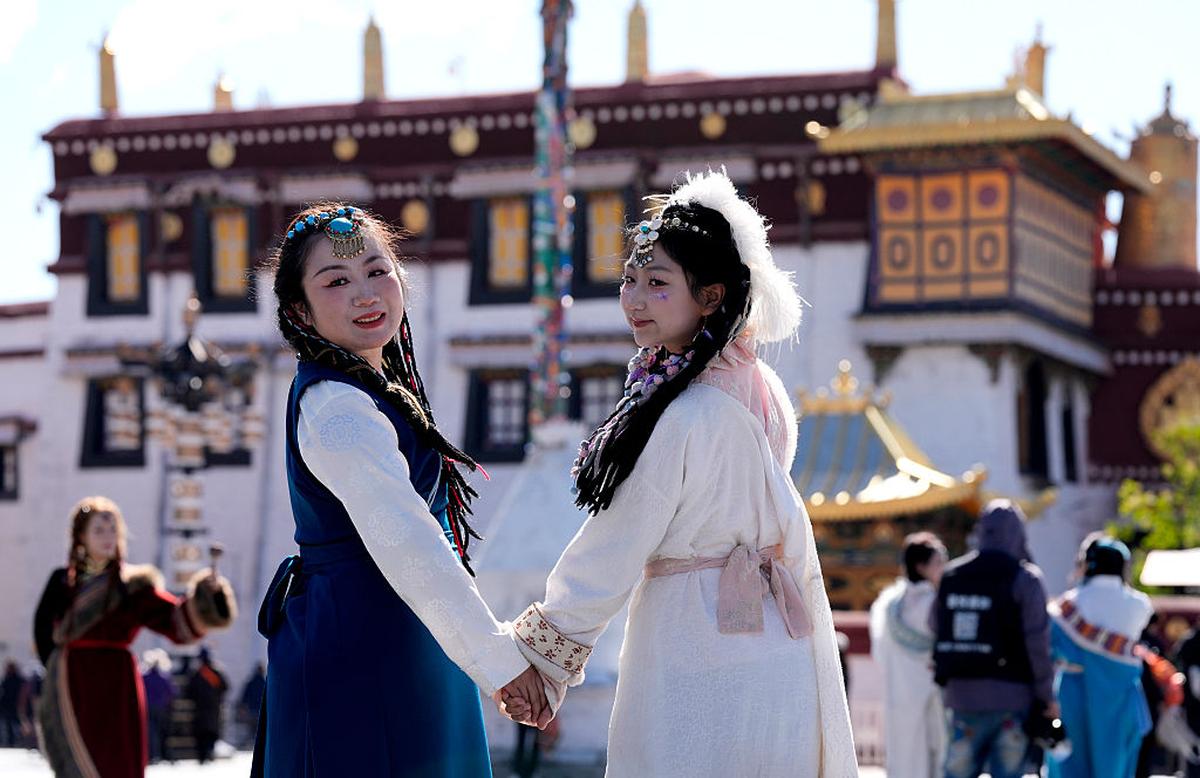 Tourists dressed in Tibetan costumes pose for photos at Jokhang Temple Square in Lhasa.