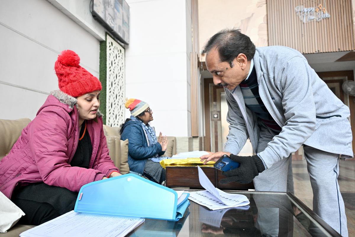 Um homem procura nomes no projeto de lista de eleitores após a revisão intensiva especial (SIR) dos cadernos eleitorais, em uma sociedade residencial em Ghaziabad, Uttar Pradesh, em 11 de janeiro de 2026. 