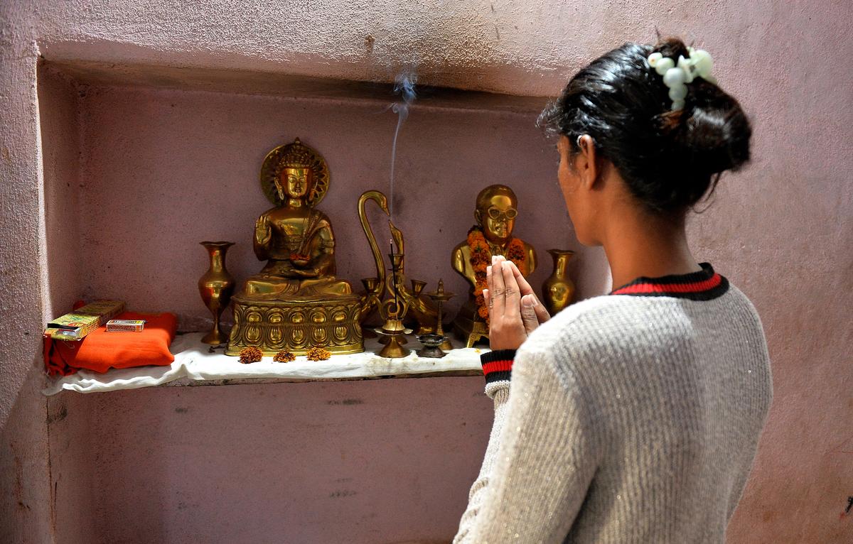 A victim of the violence offers prayers in front of statuettes of Buddha and Dr. B.R. Ambedkar at her home in Parbhani, Maharashtra.