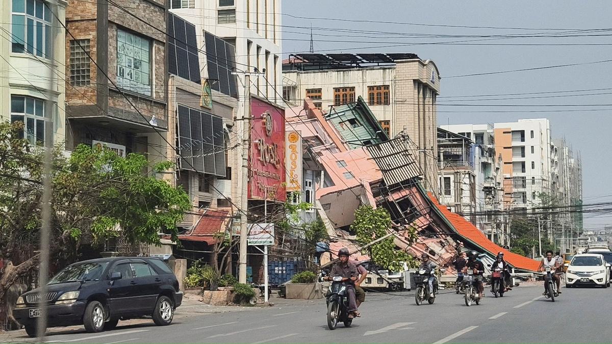 People ride motorcycles past a damaged building after a strong earthquake struck central Myanmar, in Mandalay, Myanmar, on March 28, 2025.