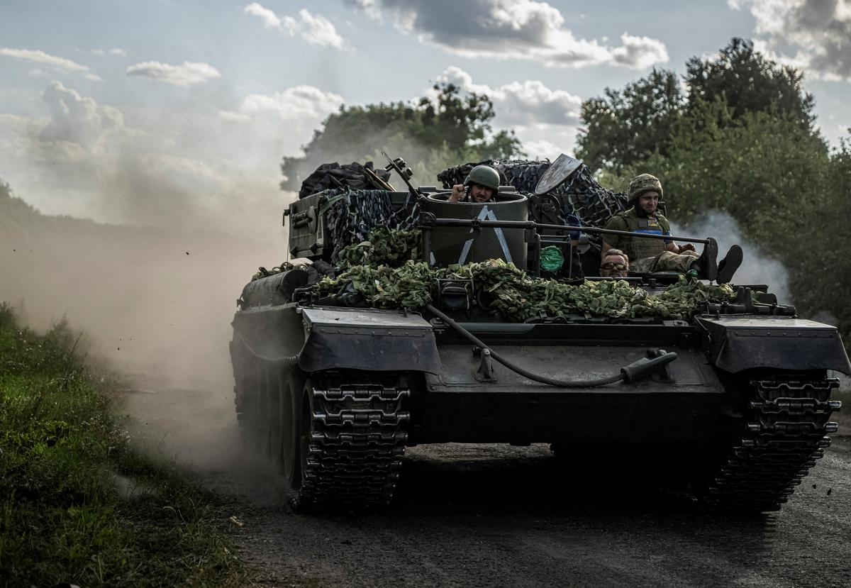 Ukrainian servicemen ride a military vehicle, amid Russia’s attack on Ukraine, near the Russian border in Sumy region.