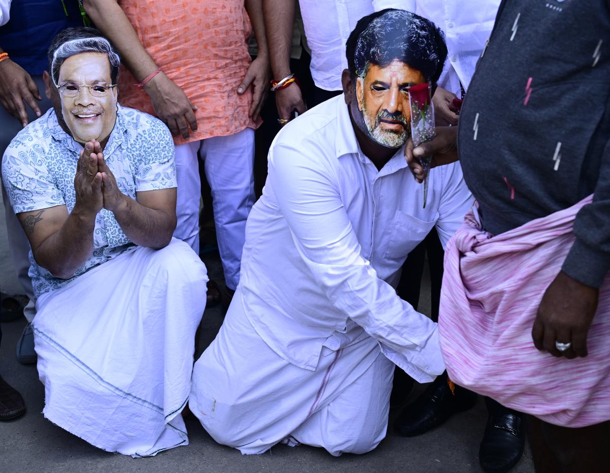 BJP workers wearing masks of Chief Minister Siddaramiah and Deputy Chief Minister D K Shivakumar, distribute roses and “apologise” to KSRTC bus passengers, during an agitation against the Karnataka government’s decision to increase bus fares by 15%, at the Kempegowda Bus Stand in Bengaluru on January 3, 2025. BJP workers wearing masks of Chief Minister Siddaramiah and Deputy Chief Minister D K Shivakumar, distribute roses and “apologise” to KSRTC bus passengers, during an agitation against the Karnataka government’s decision to increase bus fares by 15%, at the Kempegowda Bus Stand in Bengaluru on January 3, 2025.