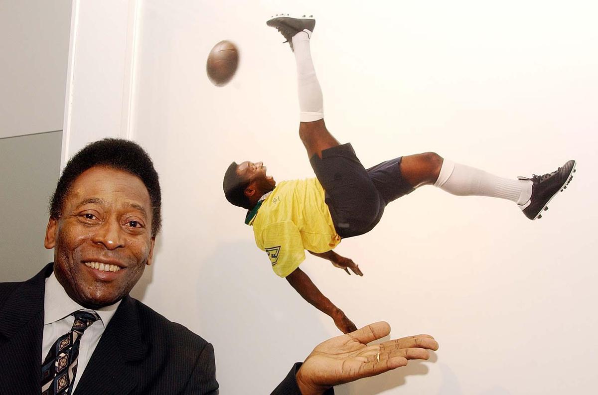 Brazilian soccer legend Pele with a photograph of himself doing an overhead scissors kick, taken by Lord Patrick Lichfield, at the launch of a photography exhibition dedicated to him in London.