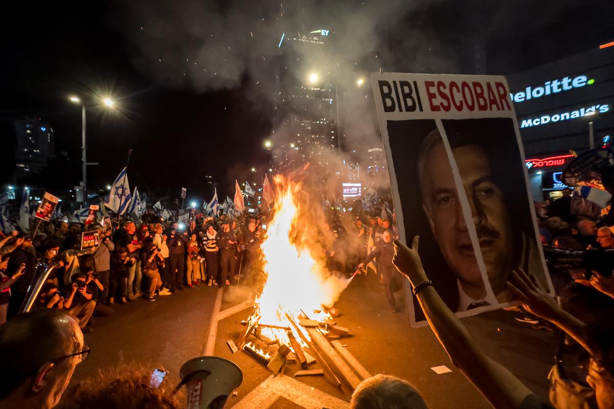 Protesters light a fire during a protest for the release of hostages and against the government and Israeli Prime Minister Benjamin Netanyahu outside The Kirya on March 16, 2024 in Tel Aviv, Israel.