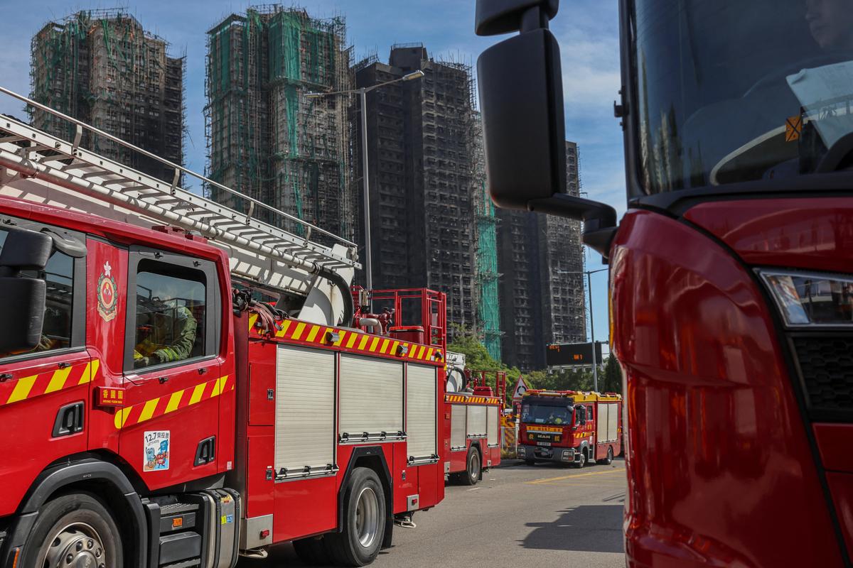 A fire truck drives past fire-damaged residential blocks at the Wang Fuk Court housing complex following a deadly fire, in Tai Po, Hong Kong, on November 28, 2025.