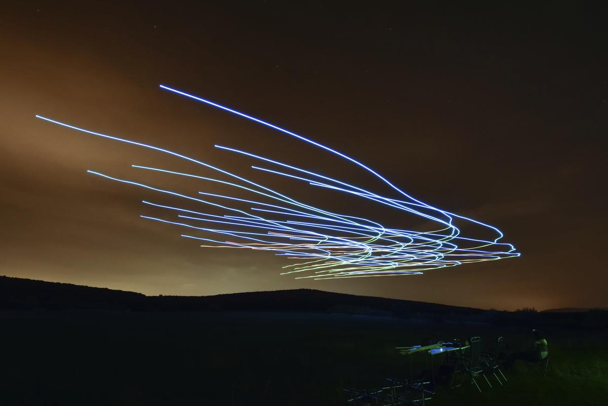 This handout photo taken with long exposure shows a researcher of the Eötvös Loránd University observing the flight of a flock of autonomous drones during an experiment near Budapest, Hungary, Thursday, Oct. 21, 2021. 