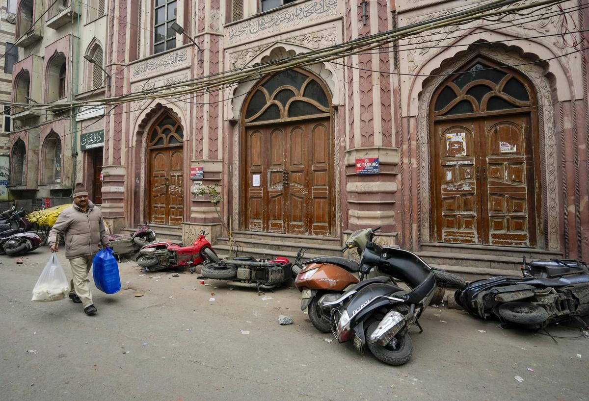 A man walks past several two-wheeler lying on a roadside after violence erupted during a demolition drive of alleged encroachments from a land adjoining the Syed Faiz Elahi mosque and a nearby graveyard