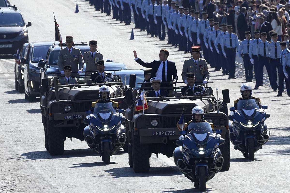 French President Emmanuel Macron waves from the command car as he drives down the Avenue Foch during the Bastille Day parade, Sunday, July 14, 2024 in Paris. 