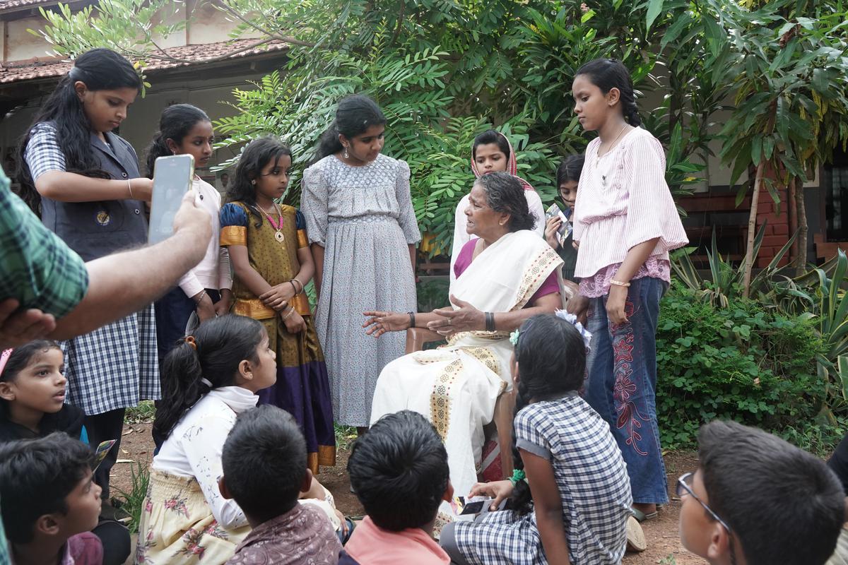 An elderly woman telling a story and children listening to the story