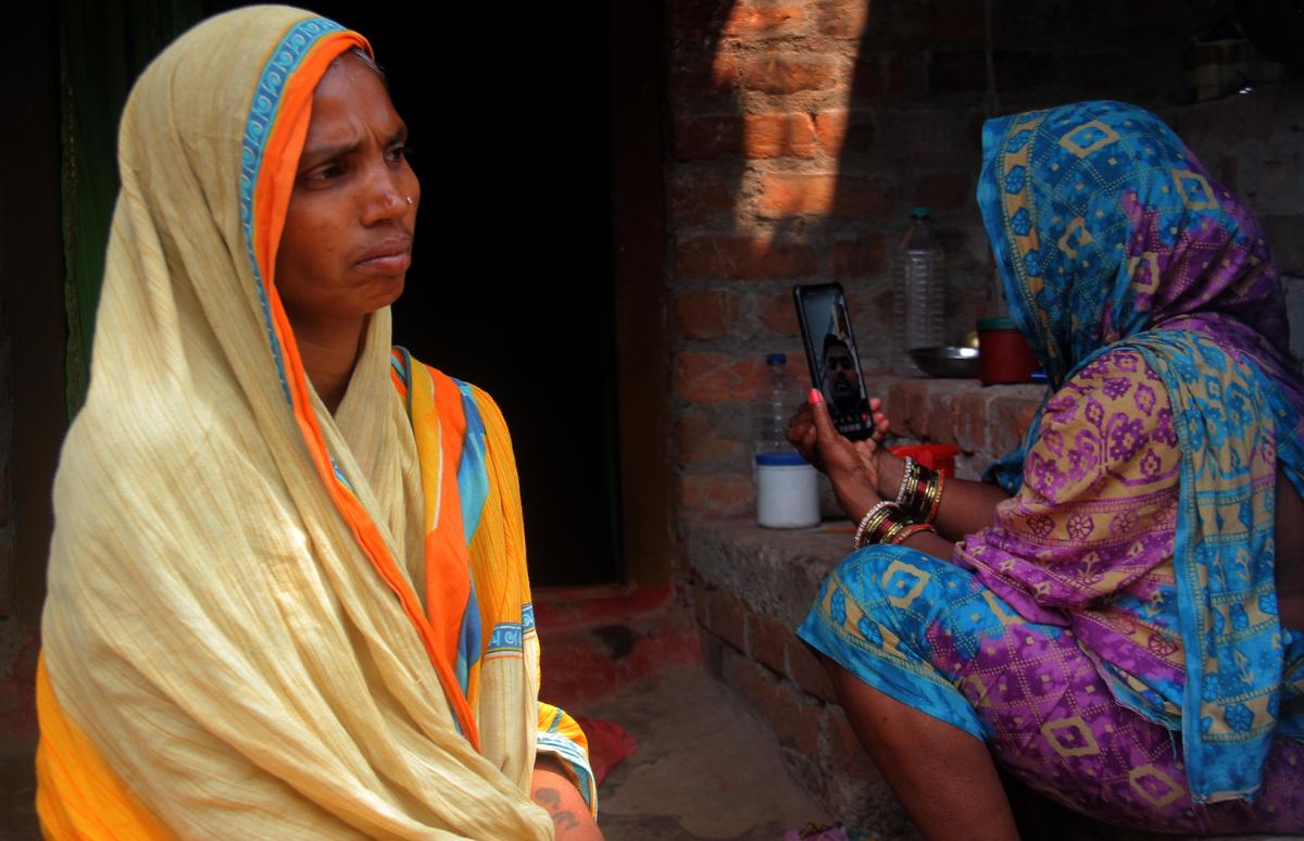 A woman takes a video call with her son, who is going to work in the Gulf region from their native village, Manikapur, in Ganjam district, Odisha.