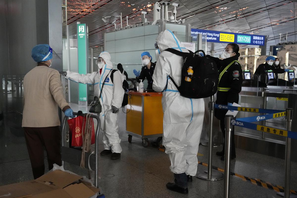 Passengers in protective gear are directed to a flight at a Capital airport terminal in Beijing. 