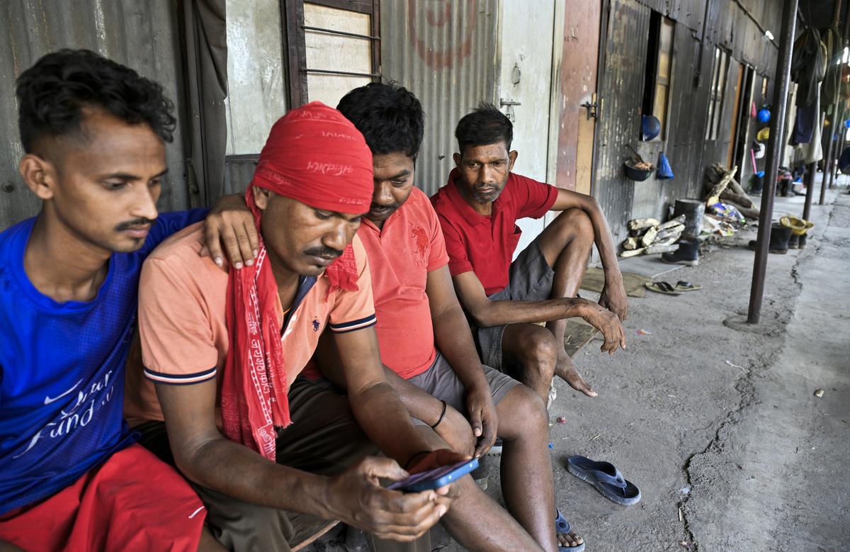 Daily wage workers from Jharkhand look for updates on the rescue operation near Domalapenta village.