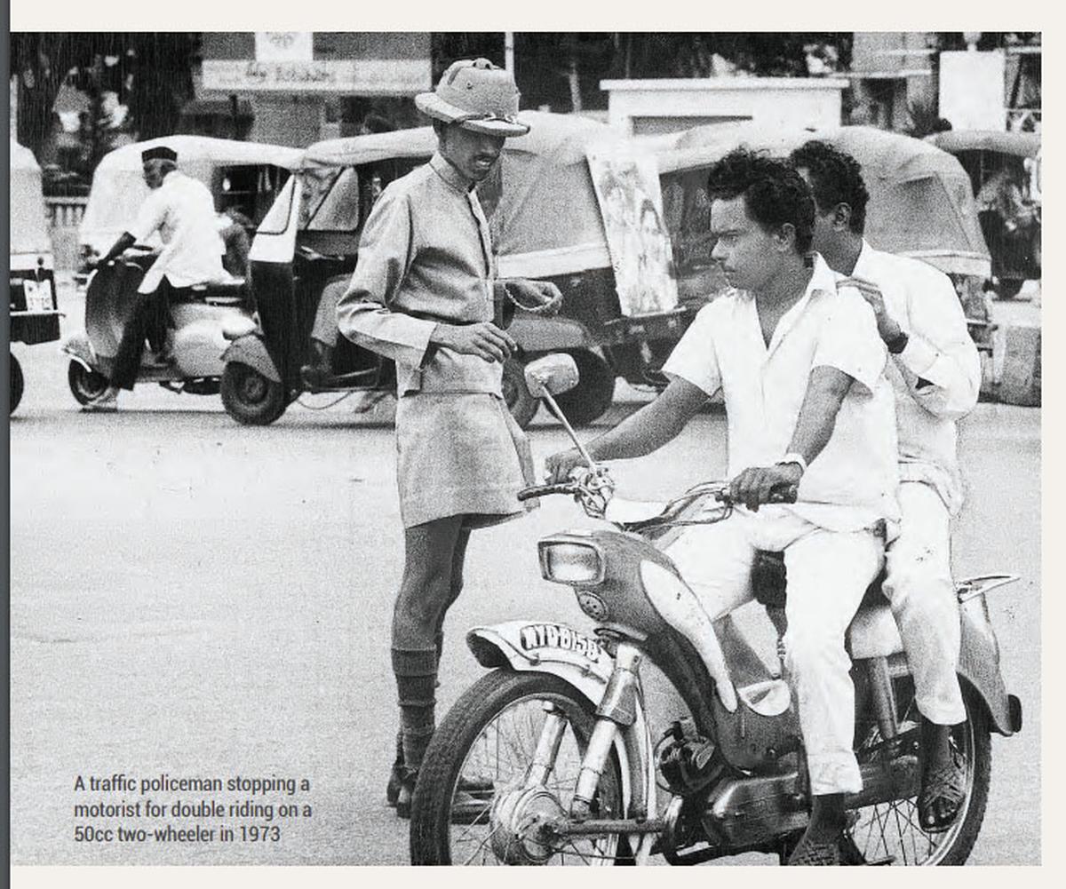 A traffic policeman stopping a motorist for pillion-riding on a 50cc two-wheeler in 1973.