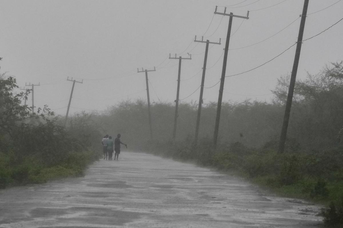 People walk along a road during the passing of Hurricane Melissa in Rocky Point, Jamaica, on October 28, 2025. 