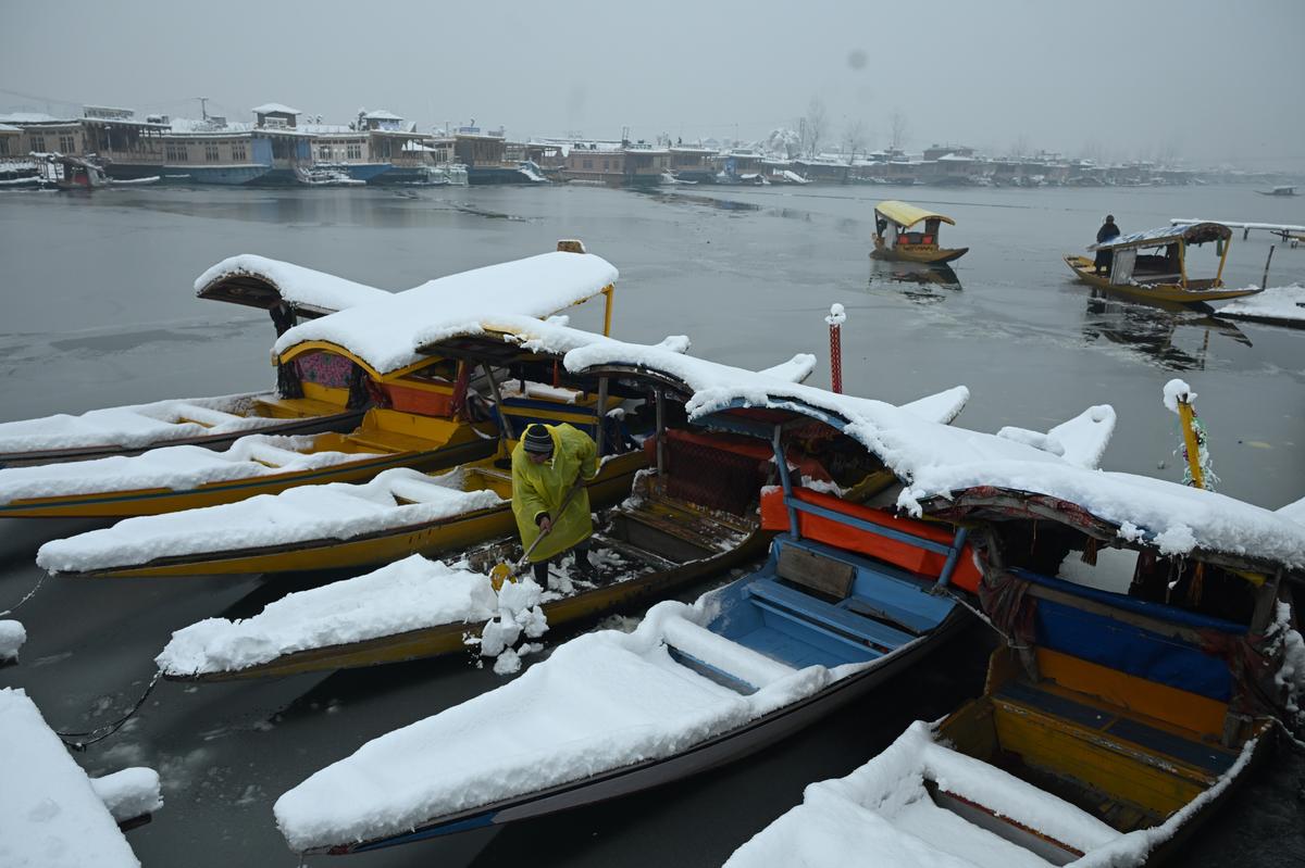 A boatman cleared snow on his Shikara Dal lake during heavy snowfall in Srinagar, 28 December 2024. 
