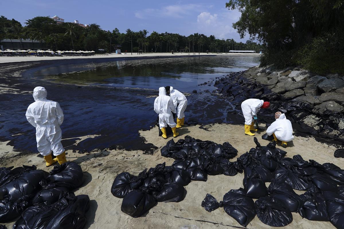 Workers clean up an oil spill along Sentosa’s Tanjong Beach area in Singapore.