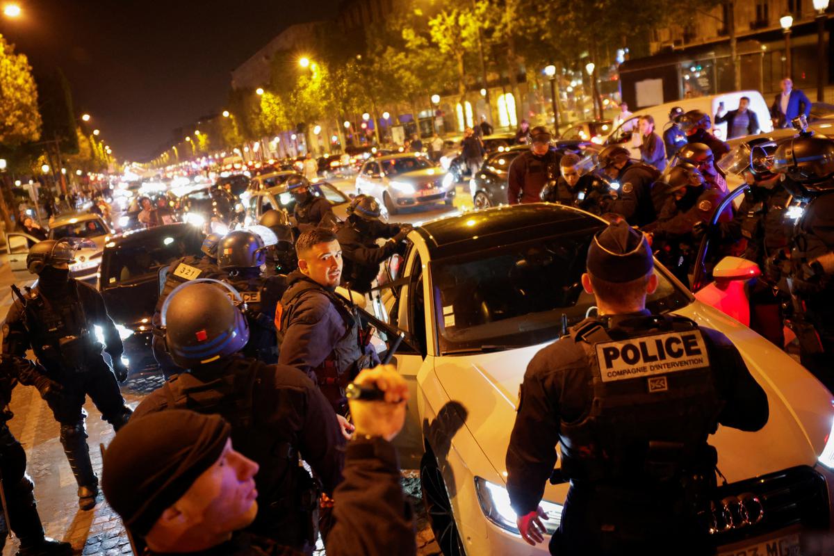 पेरिस, फ्रांस के चैंप्स एलिसीज़ क्षेत्र में ट्रैफिक रोकने के दौरान नैनटेरे में एक फ्रांसीसी पुलिस अधिकारी द्वारा मारे गए 17 वर्षीय किशोर नाहेल की मौत के बाद पांचवीं रात के विरोध प्रदर्शन के दौरान पुलिस ने युवाओं को एक वाहन के खिलाफ पकड़ लिया। 2 जुलाई 2023 को. 