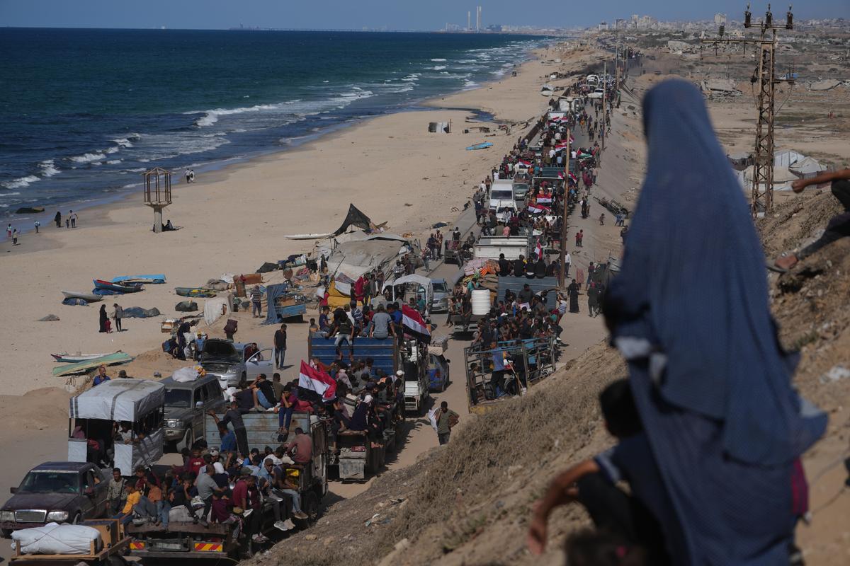 Displaced Palestinians ride on trucks loaded with belongings and wave Egyptian and Palestinian flags as they travel along the coastal road near Wadi Gaza in the central Gaza Strip, moving toward Gaza City, after Israel and Hamas agreed to a pause in their war and the release of the remaining hostages. 