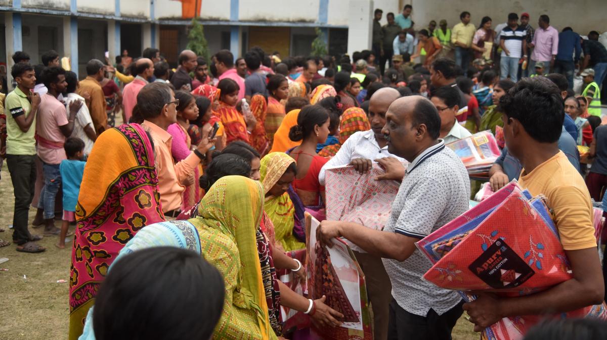 Families wait in queue to receive releief in Pallalpur high school in Malda district.