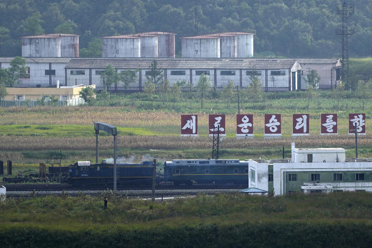 A green train with yellow trimmings, resembling one used by North Korean leader Kim Jong Un on his previous travels, is seen steaming by a slogan which reads “Towards a new victory” on the North Korea border with Russia and China seen from China’s Yiyanwang Three Kingdoms viewing platform in Fangchuan in northeastern China’s Jilin province on September 11, 2023. 