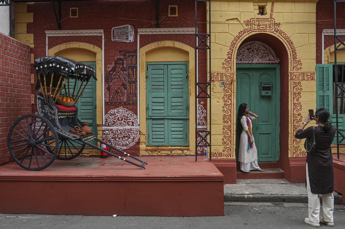 A young woman poses for pictures at a Durga Puja pandal, themed on the ‘Maha Alaye Maa’, in Kolkata