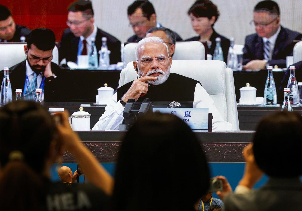 Journalists take images of a screen broadcasting Prime Minister Narendra Modi attending the plenary session of the 2025 Shanghai Cooperation Organisation (SCO) summit in Tianjin, on September 1, 2025.