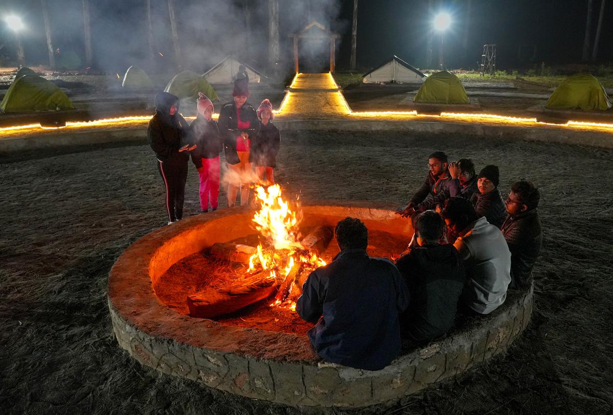 A group of tourists sitting around a bonfire to protect themselves from cold weather at Araku Pinery, a new tourist attraction by Forest department in Araku Valley.