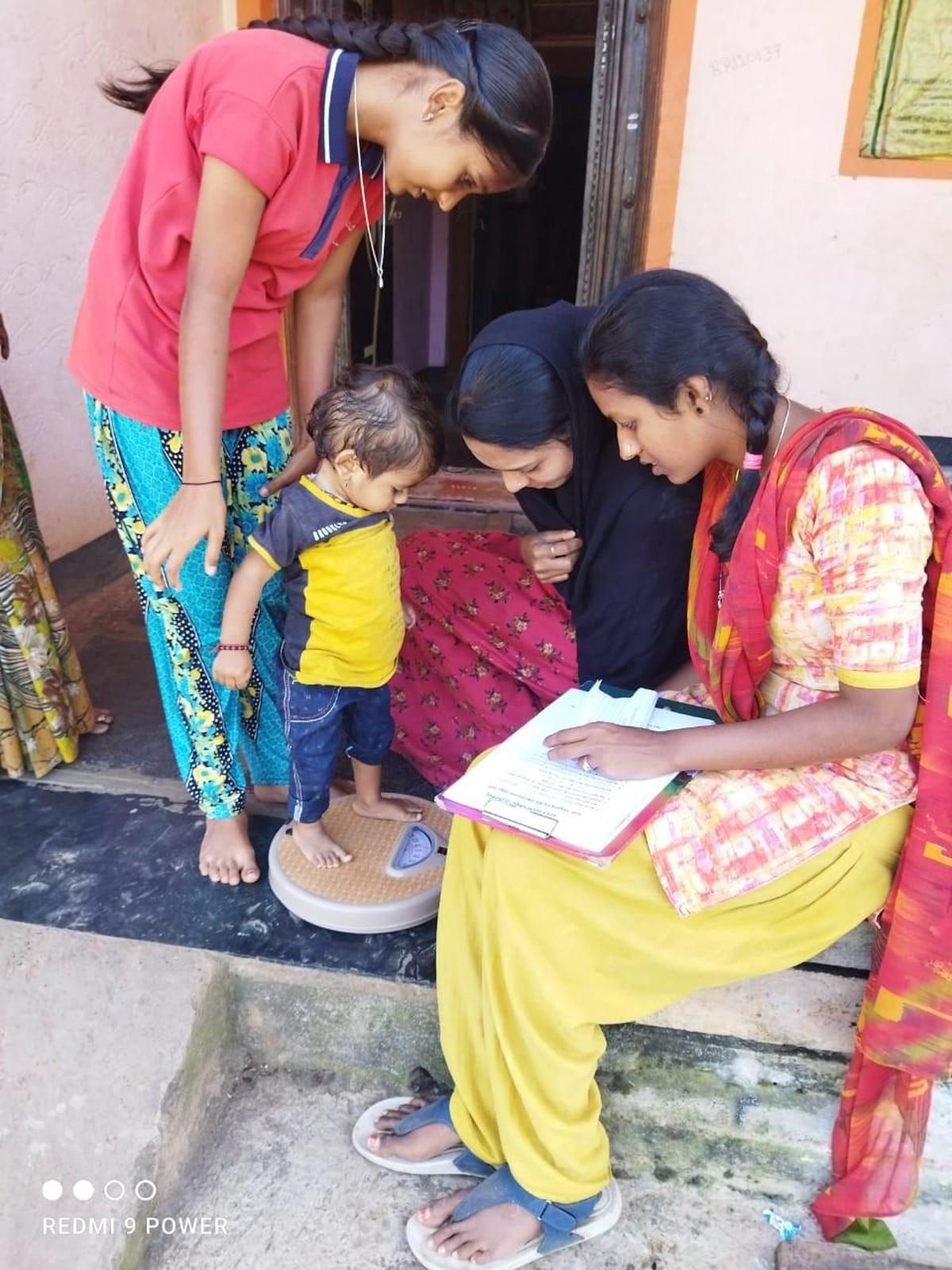 Activists of Jagruti Mahila Okkoota weigh children to assess malnutrition, in Belagavi district of Karnataka.