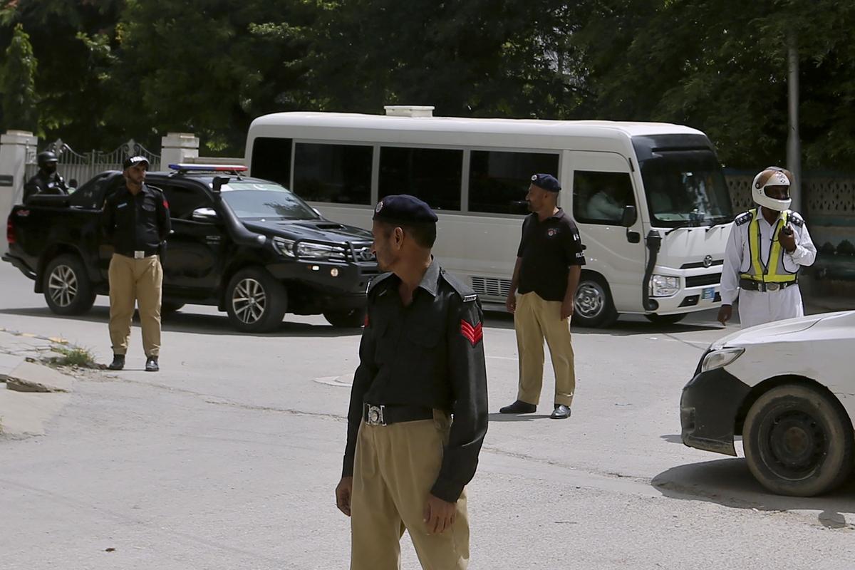 Police officers stand guard while a vehicle carrying England cricket team on way to hotel upon their arrival, in Karachi, Pakistan.