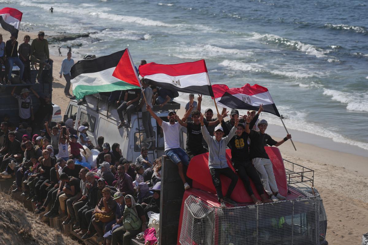 Displaced Palestinians ride on trucks loaded with belongings and wave Egyptian and Palestinian flags as they travel along the coastal road near Wadi Gaza in the central Gaza Strip, moving toward Gaza city, Saturday, on Oct. 11, 2025, after Israel and Hamas agreed to a pause in their war and the release of the remaining hostages. 