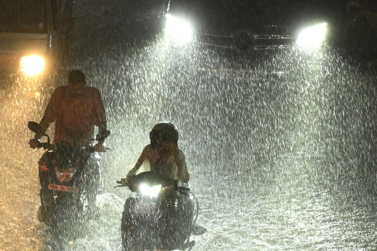 Commuters move amid heavy rainfall in Secunderabad on Sunday (September 14, 2025). 