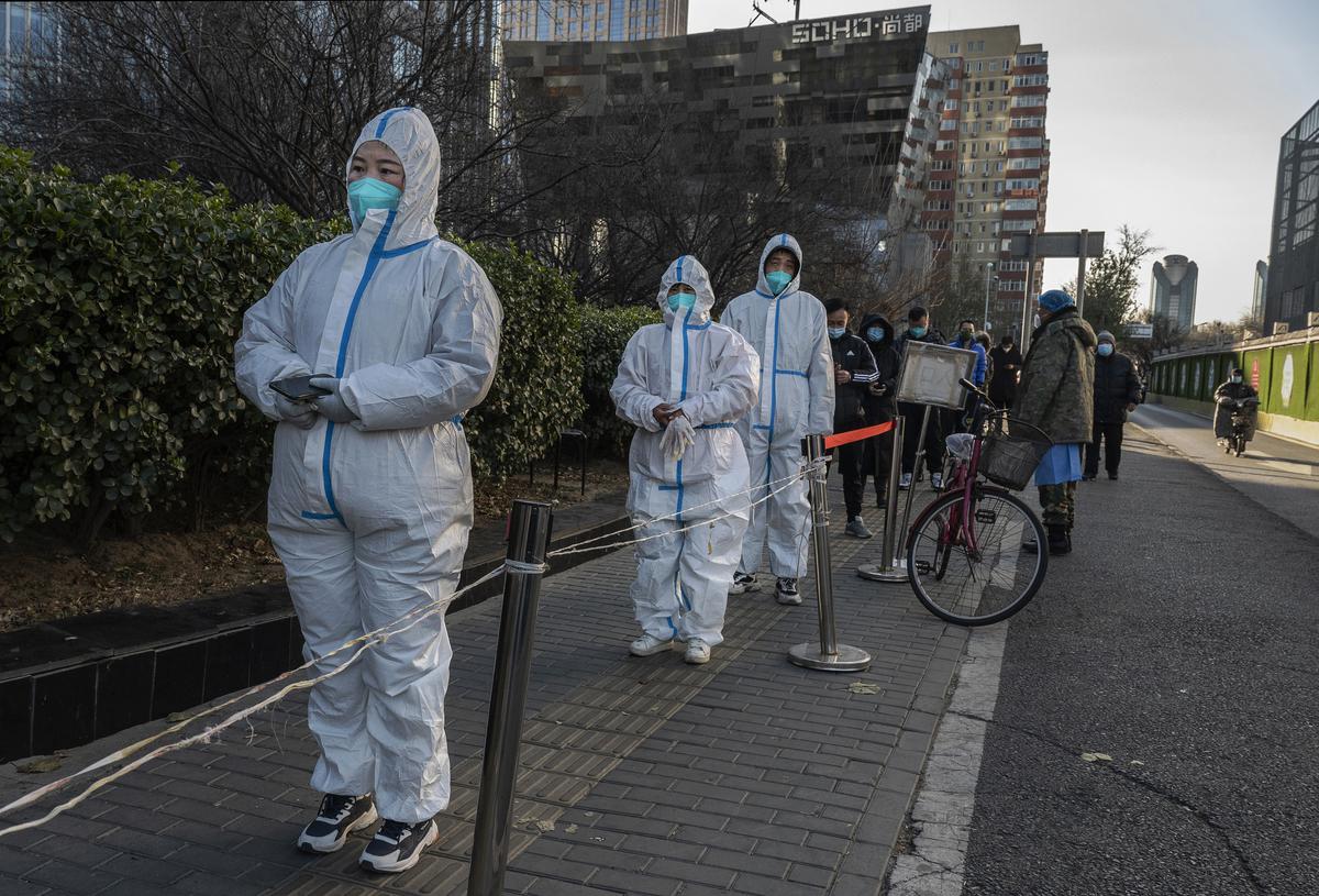 Epidemic control workers wear PPE as they line up wth others in the cold for nucleic acid tests to detect COVID-19 at a public testing site on December 4, 2022 in Beijing, China. 