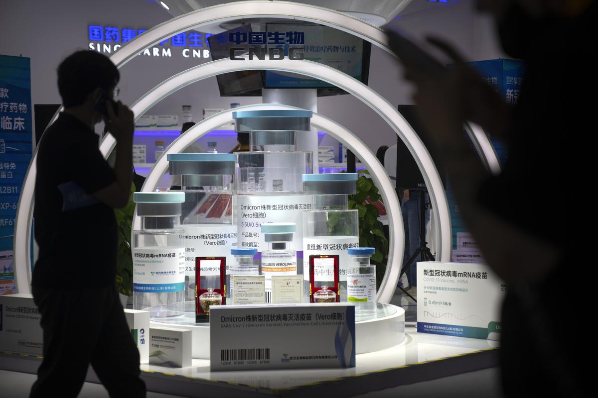 Visitors walk past a display showing mock-ups of COVID-19 and omicron variant vaccines from Chinese drugmaker Sinopharm at the China International Fair for Trade in Services (CIFTIS) in Beijing, on September 2, 2022. 