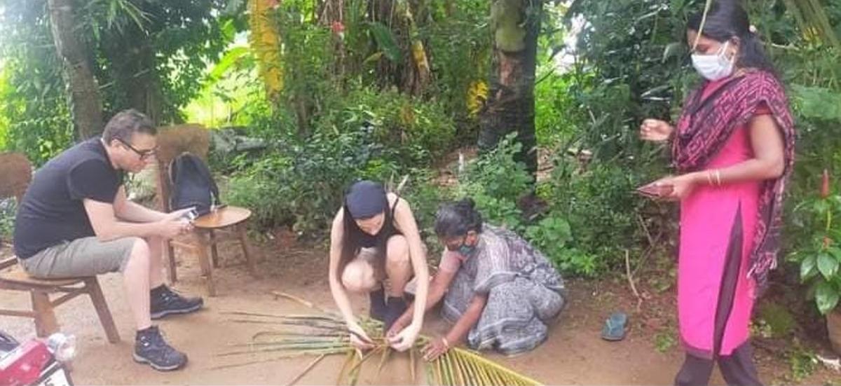 Toeristen proeven van het dorpsleven in Aymanam in Kottayam, waar ze rieten kokospalmbladeren proberen te leren van een lokale inwoner