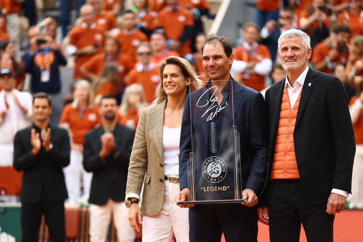     Rafael Nadal berpose dengan plakat peringatan bersama dengan direktur turnamen Amelie Mauresm dan presiden FFT, Gilles Moretton selama upacara upeti -nya