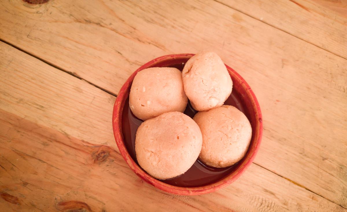 nolen gur rosogolla or rasgulla served on plate. brown spongy bengali indian traditional sweet made from cottage cheese and jaggery. winter special delicacy.copy space background. bengali story