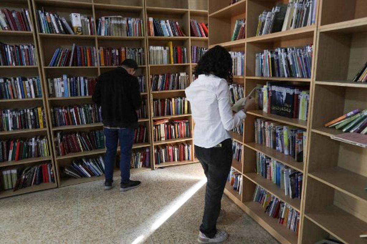 Members of the Kurdistan Centre for Arts and Culture (KCAC), select old books from the shelves before making digital copies, as part of an effort to digitise historic Kurdish volumes and manuscripts, in the northern Iraqi city of Dohuk on February 13, 2024. 