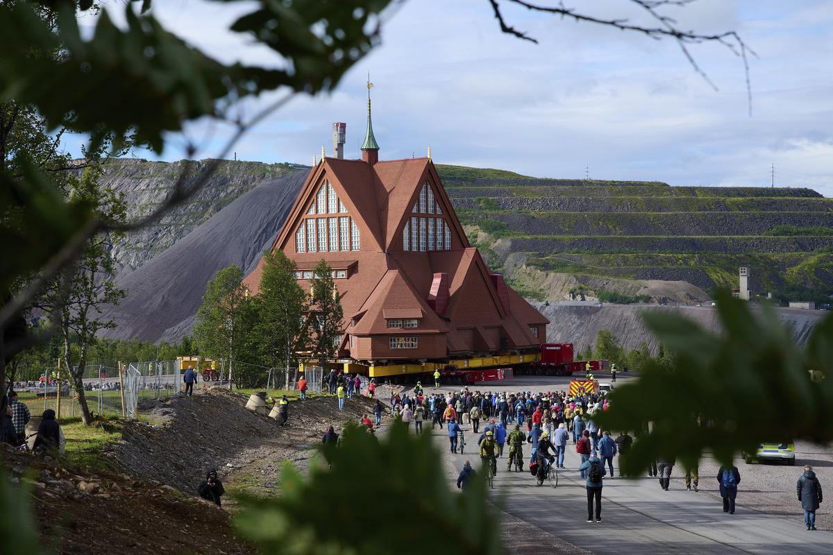 People gather outside the Kiruna Church, a Sami style wooden Swedish Lutheran church, called Kiruna Kyrka in Swedish, in Kiruna, Sweden, Tuesday, Aug. 19, 2025, during its move along a 5-kilometre (3-mile) route east to a new city centre as part of the town’s relocation. 