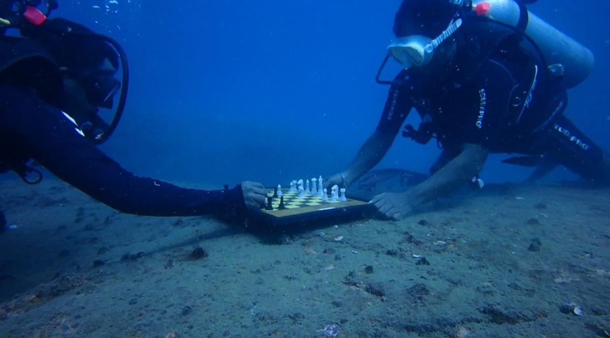 Scuba divers playing a game of chess underwater.