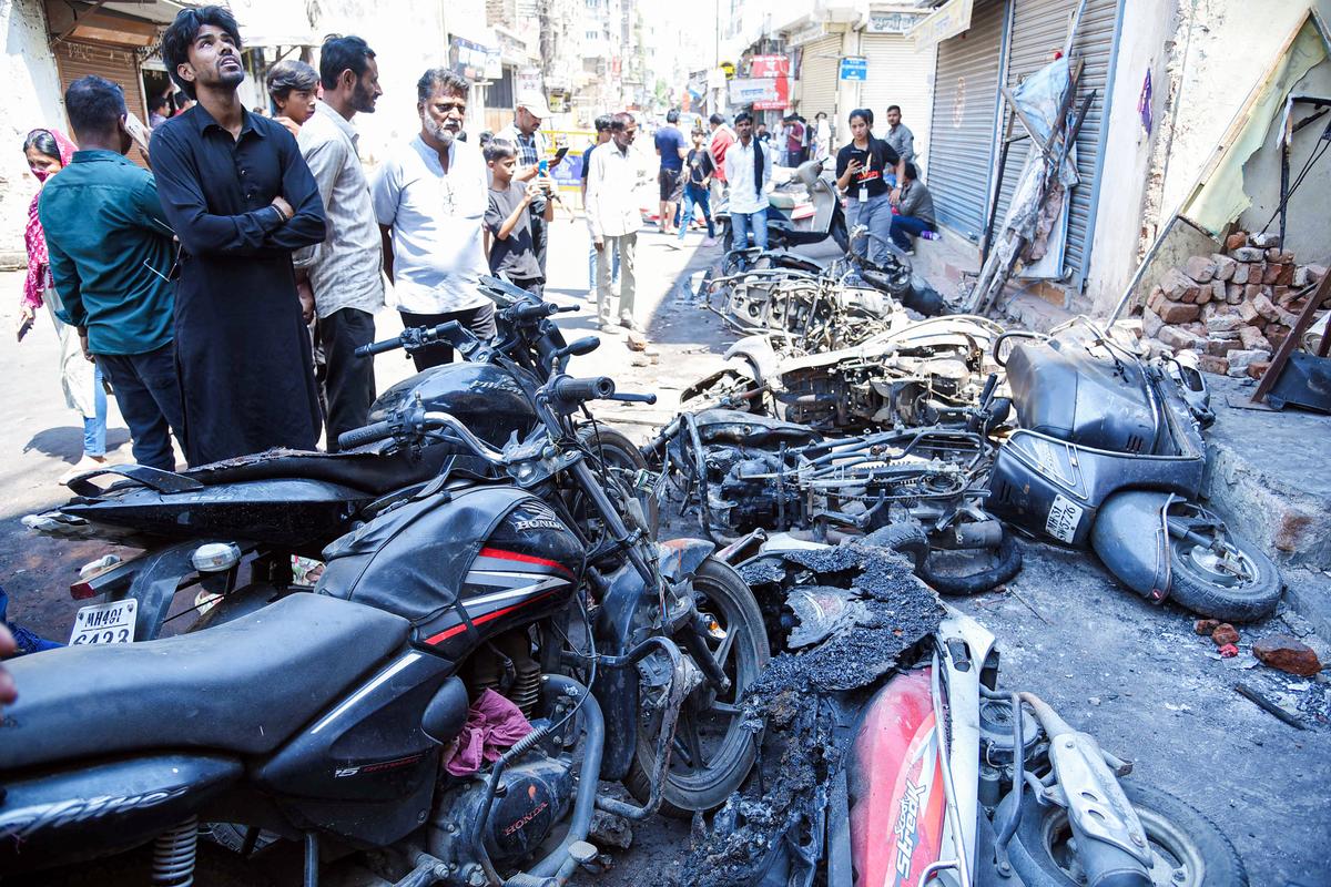 People look at the charred remains of vehicles after a clash broke out between two groups on Mar 17th, in Nagpur on March 18, 2025.