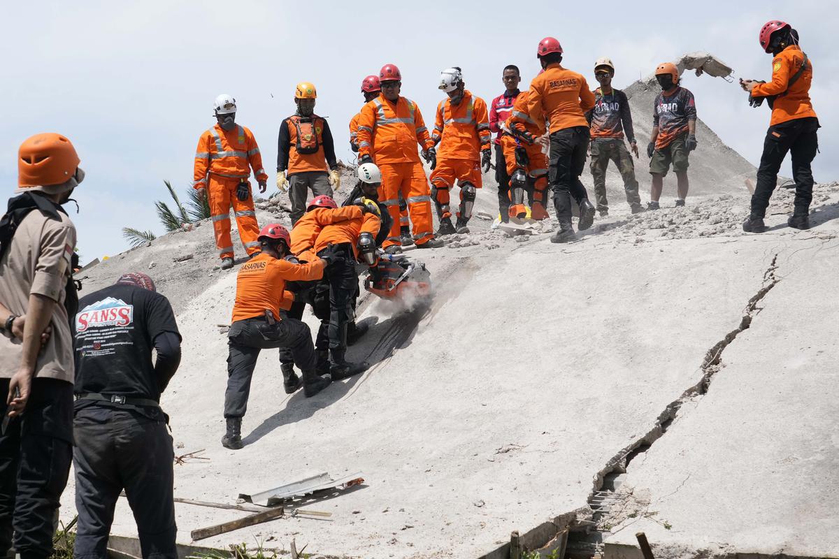 Rescuers cut through cement to  recover the body of an earthquake victim from under the rubble of a collapsed building in Cianjur, West Java, Indonesia on November 22, 2022.
